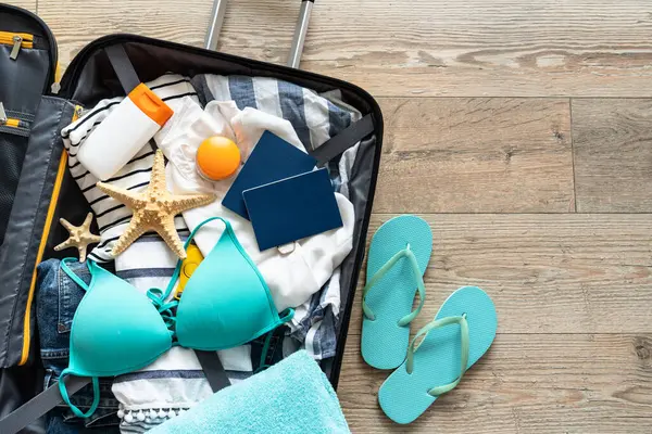 İçinde yazlık kumaş, şapka ve pasaport olan bavulu aç. Seyahat konsepti. Metin için alanı olan düz resim.