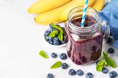 Mavi arka planda cam kavanozda yabanmersini muzlu smoothie..