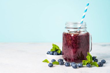 Mavi arka planda taze böğürtlenli cam kavanozda yabanmersini püresi..