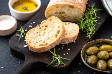 Yunan yemekleri, Akdeniz yemekleri. Siyah masada zeytinyağı, zeytin ve biberiye ile ciabatta ekmeği.