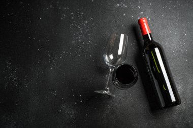 Siyah arka planda şarap şişesi ve şarap kadehi. Kopyalama alanı olan üst görünüm.
