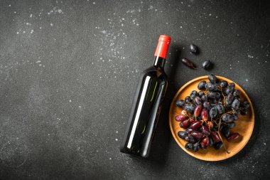 Siyah arka planda şarap şişesi ve üzüm. Kopyalama alanı olan üst görünüm.