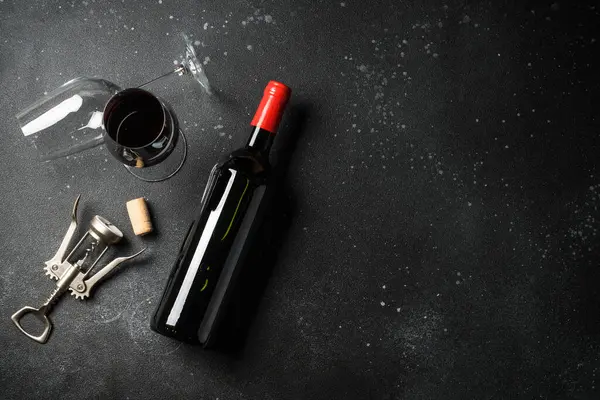 Kırmızı şarap siyah arka planda. Bir bardak şarap, şişe ve tirbuşon. Kopyalama alanı olan düz resim.
