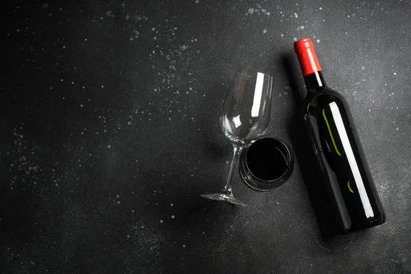 Siyah arka planda şarap şişesi ve şarap kadehi. Kopyalama alanı olan üst görünüm.
