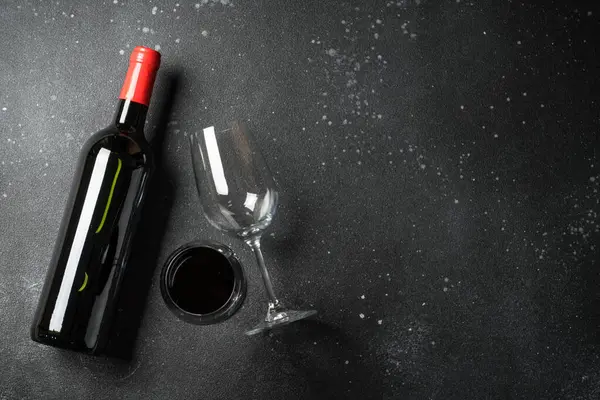 Siyah arka planda şarap şişesi ve şarap kadehi. Kopyalama alanı olan üst görünüm.
