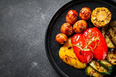 Siyah arka planda ızgara sebzeler. Patates, biber, kabak, patlıcan ve domates. Barbekü tabağı, vejetaryen. Kopyalama alanı olan üst görünüm.