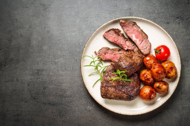 Sebzeli et biftekleri ve siyah arka planda otlar. Kopyalama alanı olan üst görünüm.