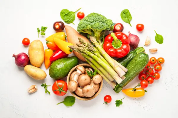 Beyaz arka planda sebzeler. Sağlıklı yemekler, vejetaryen yemekleri, manzarası. Paprika, kuşkonmaz, domates, brokoli ve avokado..