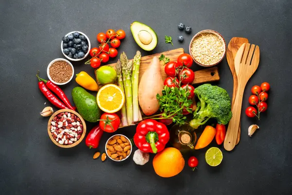 Siyah arka planda sağlıklı yiyecek çeşitleri. Taze sebze, tahıl, yaprak ve fındık. Üst görünüm.