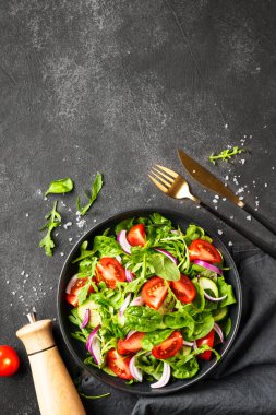 Yapraklı ve sebzeli taze salata. Siyah üzerine üst görünüm.