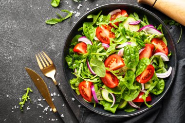 Taze yapraklı ve sebzeli yeşil salata. Siyah üzerine üst görünüm.