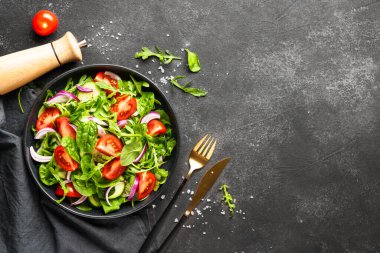 Yapraklı ve sebzeli taze salata. Siyah üzerine üst görünüm.