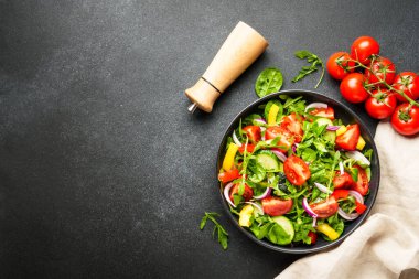 Yapraklı ve sebzeli taze salata. Üst görünüm siyah, dizayn için boşluk.