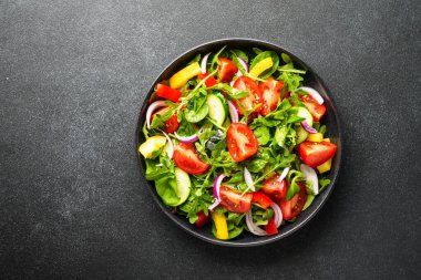 Yapraklı ve sebzeli taze salata. Siyah üzerine üst görünüm.