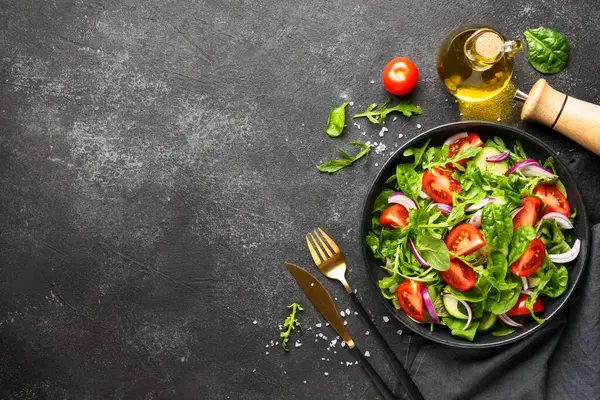 Yapraklı ve sebzeli taze salata. Siyah üzerine üst görünüm.