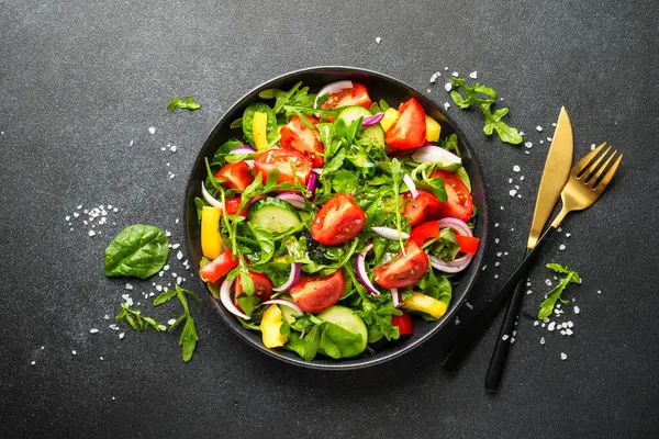 Taze yapraklı ve sebzeli yeşil salata. Siyah üzerine üst görünüm.