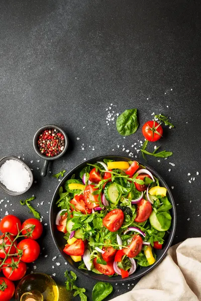 Yapraklı ve sebzeli taze salata. Üst görünüm siyah, dizayn için boşluk.