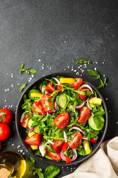 Yapraklı ve sebzeli taze salata. Üst görünüm siyah, dizayn için boşluk.