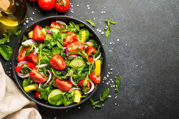 Yapraklı ve sebzeli taze salata. Siyah üzerine kopyalama alanı olan üst görünüm.