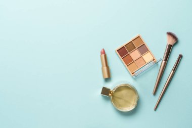 Mavi arka planda ürünler ve parfüm var. Kopyalama alanı olan üst görünüm.