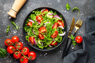 Yapraklı ve sebzeli taze salata. Siyah üzerine üst görünüm.