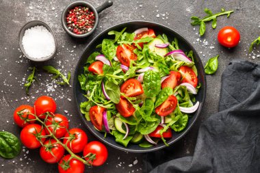 Yapraklı ve sebzeli taze salata. Siyah üzerine üst görünüm.