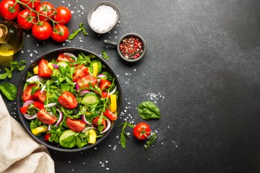Yapraklı ve sebzeli taze salata. Siyah arkaplanda tasarım için alanı olan üst görünüm.