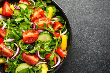 Siyah arka planda sağlıklı yiyecekler. Yapraklı salata, domates, biber ve zeytinyağı. Siyaha yaklaş..