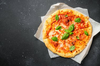 Siyah arka planda fesleğen yapraklı pizza Margarita. Üst görünüm, kapat.