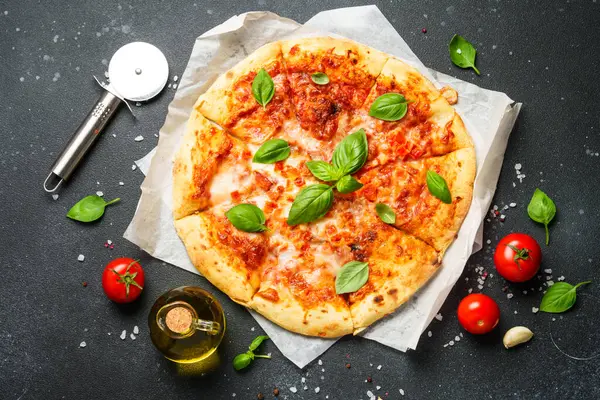 Siyah arka planda pizza margaritası ve yemek malzemeleri. Üst görünüm.