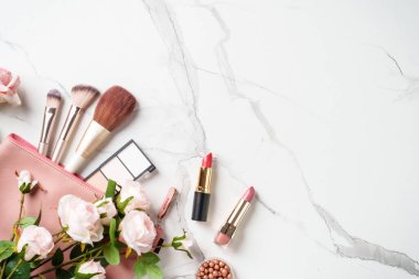 Beyaz arka planda gül çiçekli makyaj ürünleri olan kozmetik çanta. Kopyalama alanı olan düz.
