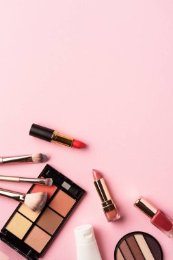 Makyaj ürünleri pembeye yatar. Göz farı, fosforlu kalem, krem, ruj ve kozmetik fırçalar..