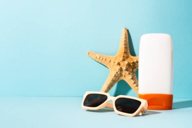 Yaz kavramı. Güneş gözlüğü, güneş kremi ve güneşli gölgeli deniz kabuğu. Moda yaz konsepti.