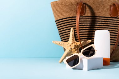 Yaz tatili konsepti. Güneş gözlüğü, güneş kremi ve mavi üzerinde güneşli gölgeler olan deniz kabuğu.