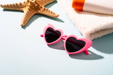Yaz tatili konsepti. Güneş gözlüğü, güneş kremi ve güneşli gölgeli deniz kabuğu.
