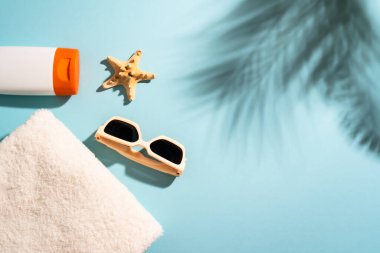 Yaz tatili konsepti. Güneş gözlüğü, güneş kremi, şapka ve güneşli gölgeli deniz kabuğu..