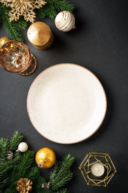 Noel sofrası. Çatal bıçaklı el işi tabaklar ve siyahta altın Noel süslemeleri. Kopyalama alanı olan düz.