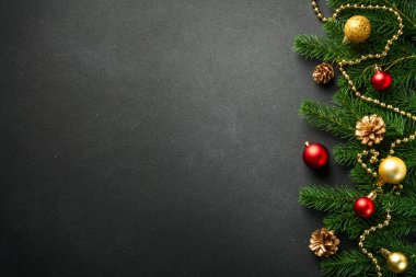 Köknar ağacı ve bayram süslemeleri ile siyah Noel arka planında yatıyordu. Tasarım için alanı kopyala.