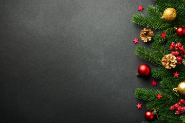 Köknar ağacı ve bayram süslemeleri ile siyah Noel arka planında yatıyordu. Tasarım için alanı kopyala.