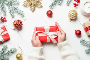 Noel hediyesi ve beyaz süslemeler. Kış tatilinde hediye paketi veren bir kadın. Kopyalama alanı olan düz.