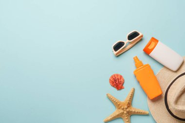 Mavi arka planda güneş kremi, güneş gözlüğü ve deniz kabuğu. Fotokopi alanı olan düz bir yer. Güneş koruma kavramı.