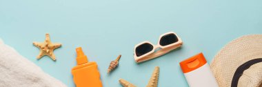 Yaz düzlüğü arka plandaydı. Şapka, havlu, güneş kremi, deniz kabuğu ve güneş gözlüğü. Metin için alanı olan uzun biçim.