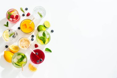 Beyaz arka planda buzlu içecekler. Limonata, mojito, ahududu limonatası, taze meyveli tonik suyu. Metin için boşluk olan üst görünüm.