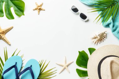 Yaz düzlüğü arka plandaydı. Palmiye yaprakları, şapka, güneş gözlükleri, beyaz arka planda deniz kabukları ve metin için boşluk..