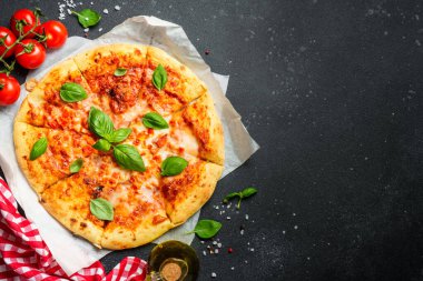 Siyah arka planda pizza margaritası ve yemek malzemeleri. Kopyalama alanı olan düz.