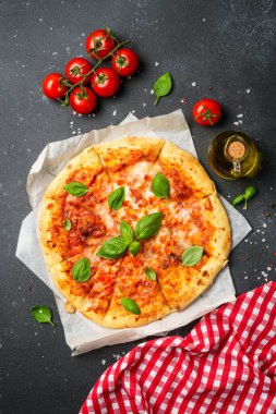 Siyah arka planda pizza margaritası ve yemek malzemeleri. Üst görünüm.