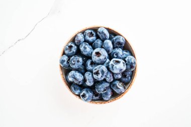 Böğürtlenler beyaz kasede. Beyaz masadaki üst görünüm.