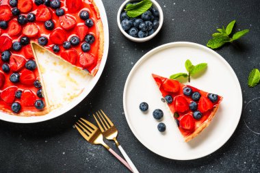 Çilekli ve yabanmersinli tart. Siyah arkaplanda üst görünüm.