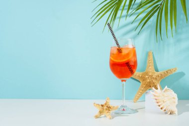 Mavi arka planda yaz alkollü kokteyl içeceği. Şarap kadehi ve güneş gözlüğü içinde Aperol Spritz, yaz tatili konsepti..