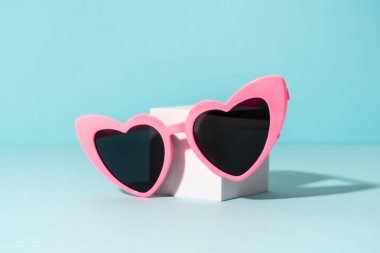 Güneşli gölgeli beyaz kürsüde güneş gözlüğü. Komik bir konsept..